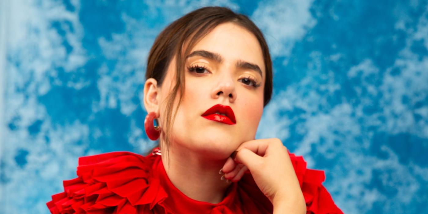 Woman in red dress sitting in front of a sky-like textured backdrop