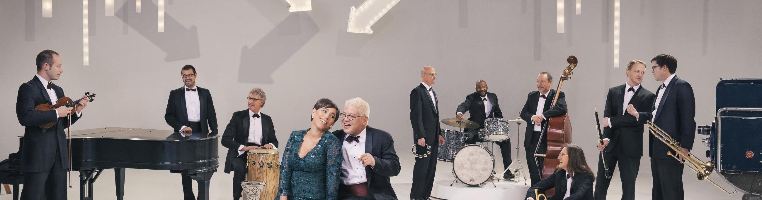 white room with people in suits and dresses standing around looking at each other