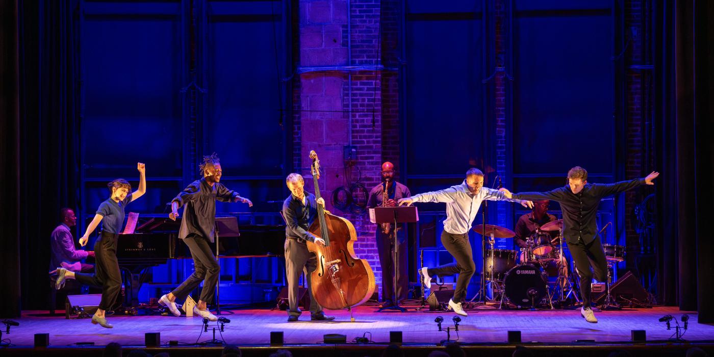 five dancers on a purple backlit stage