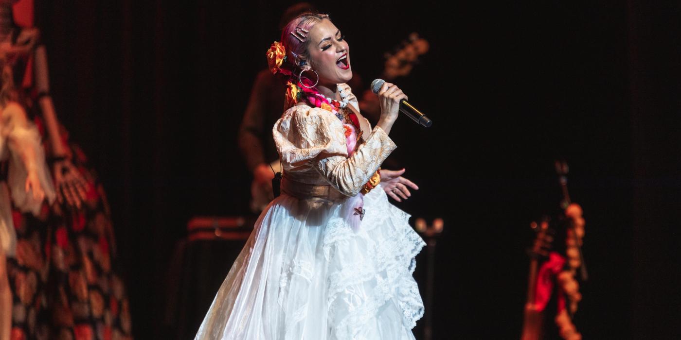 Woman in white dress singing on stage
