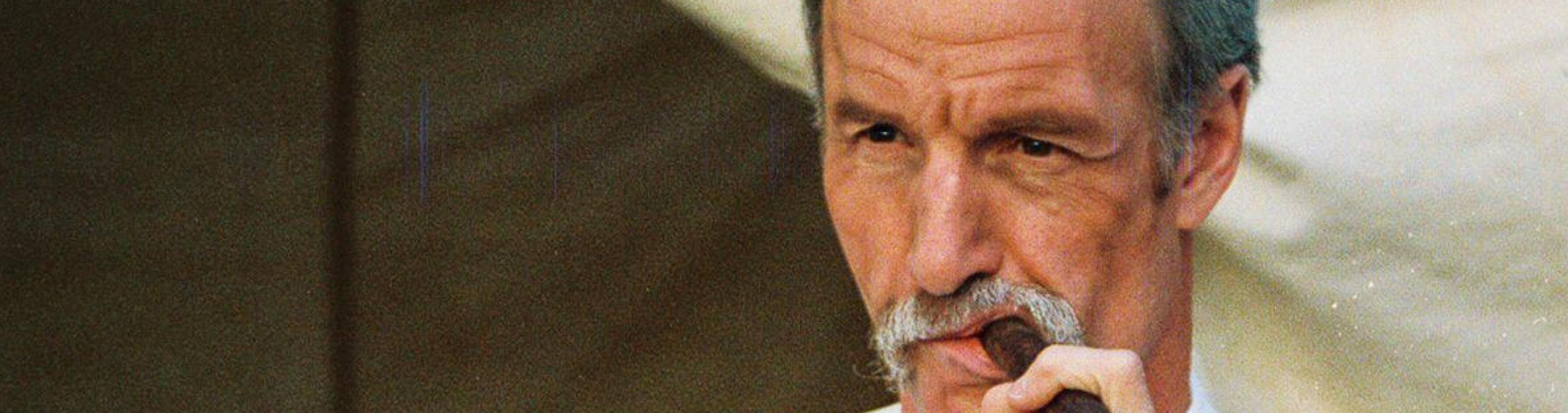 Wyatt Earp smokes a cigar while reclining in a tent.
