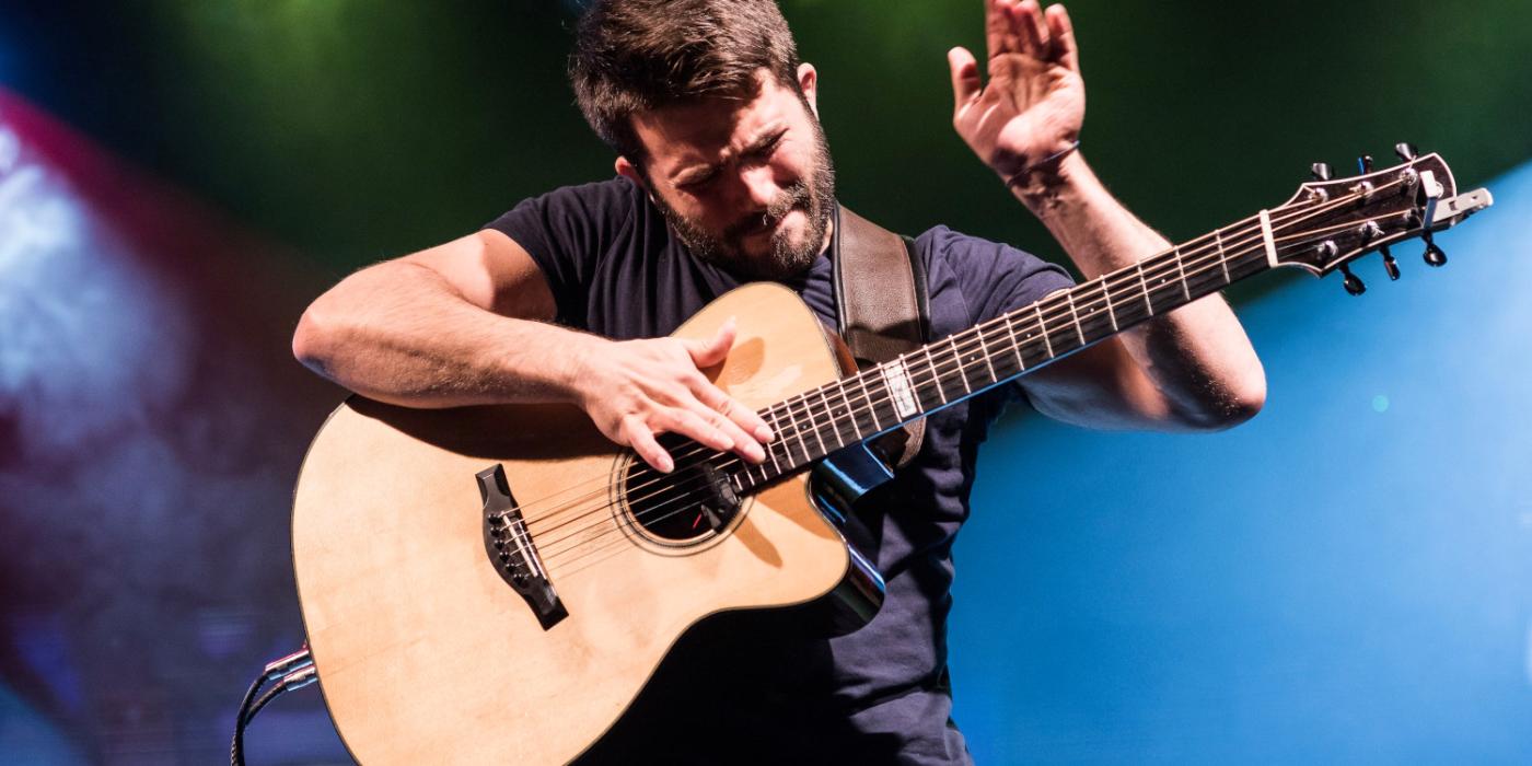 Caucasian Male playing a guitar.