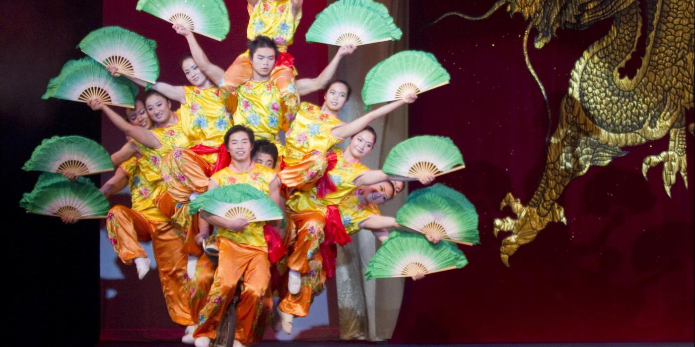 Acrobats piled riding a bike. 