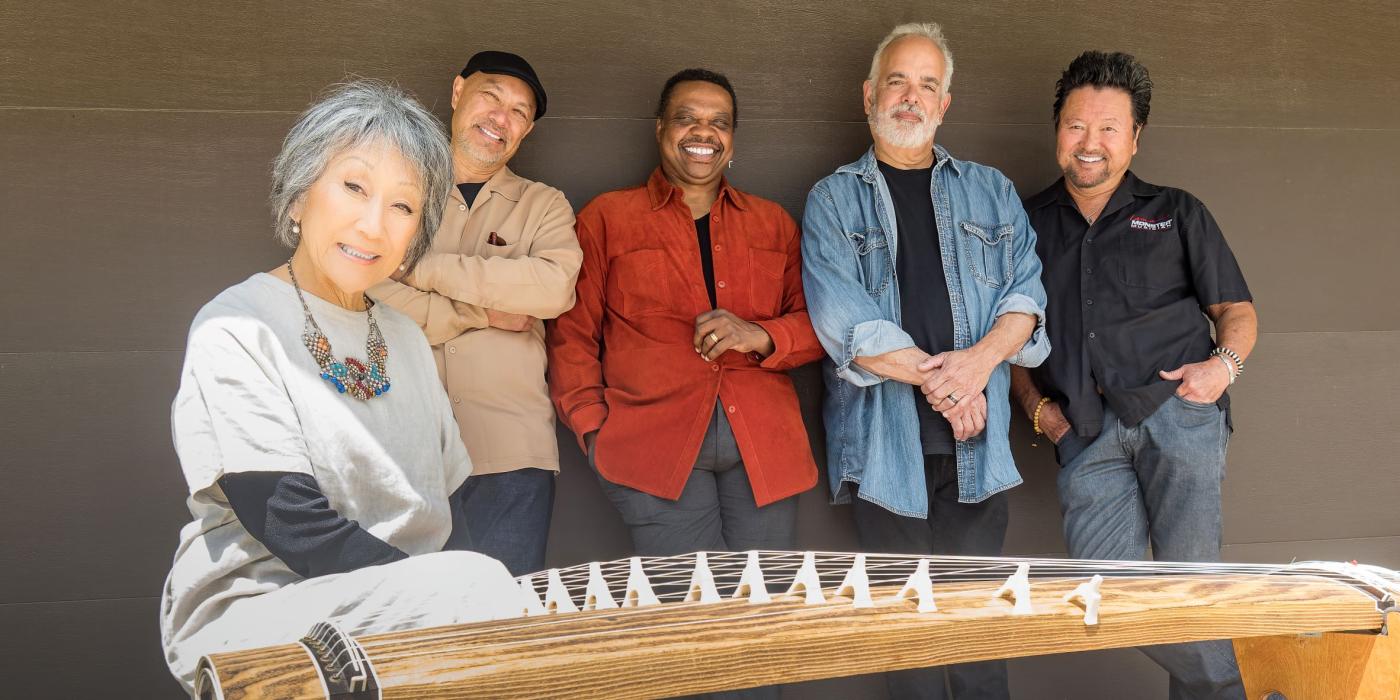 the band Hiroshima - 4 men and one woman in front of a Japanese string instrument