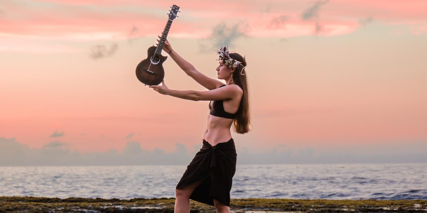 polynesian woman wearing beach attire holding an ukulele. 