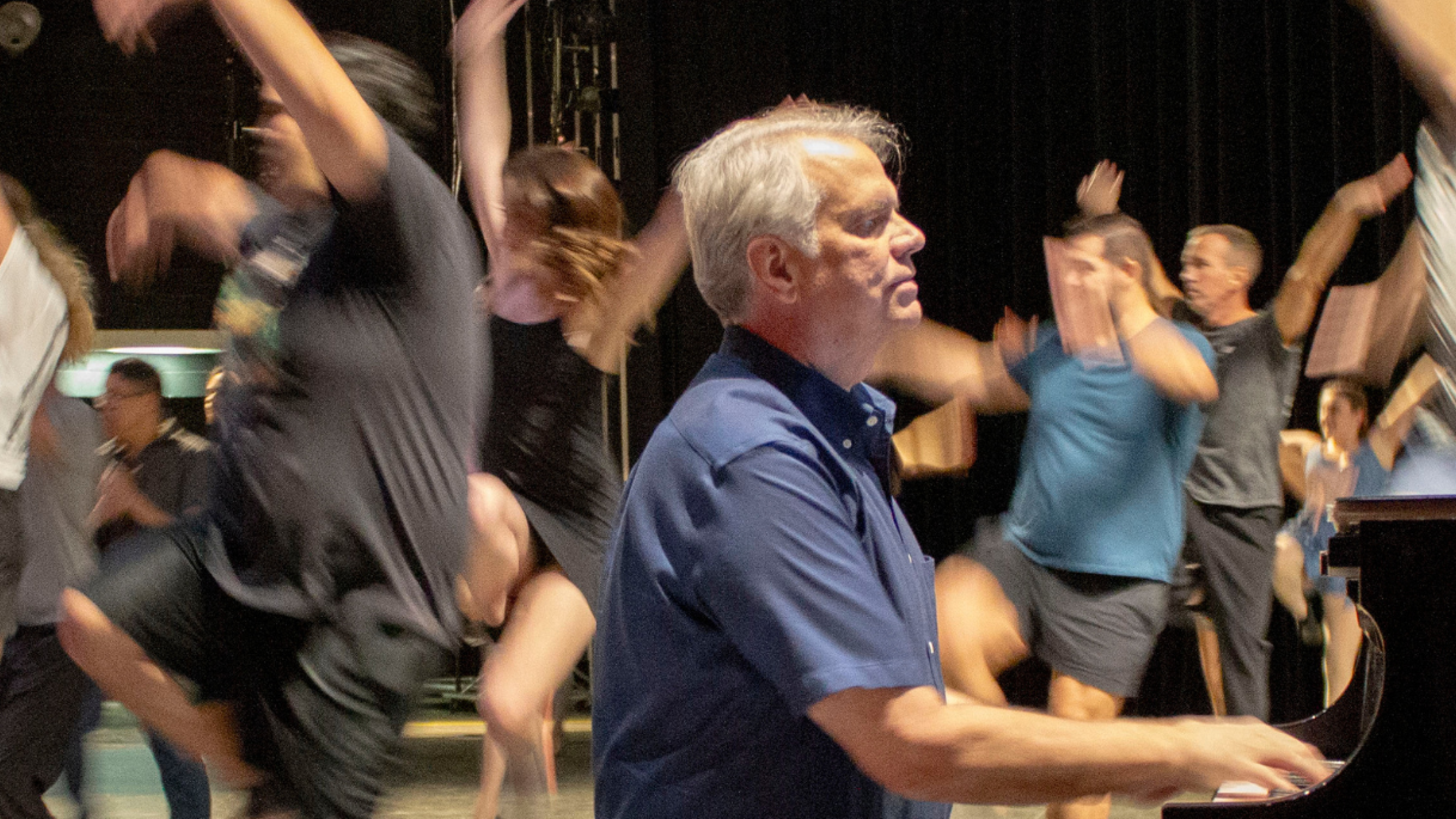 pianist playing while a theatrical audition takes place behind him.